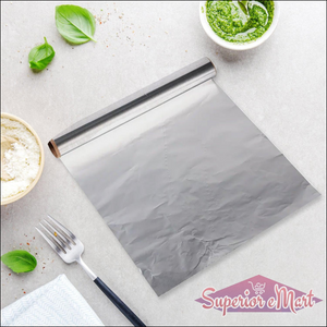Heavy duty aluminum foil roll laid out on a kitchen countertop with fresh ingredients