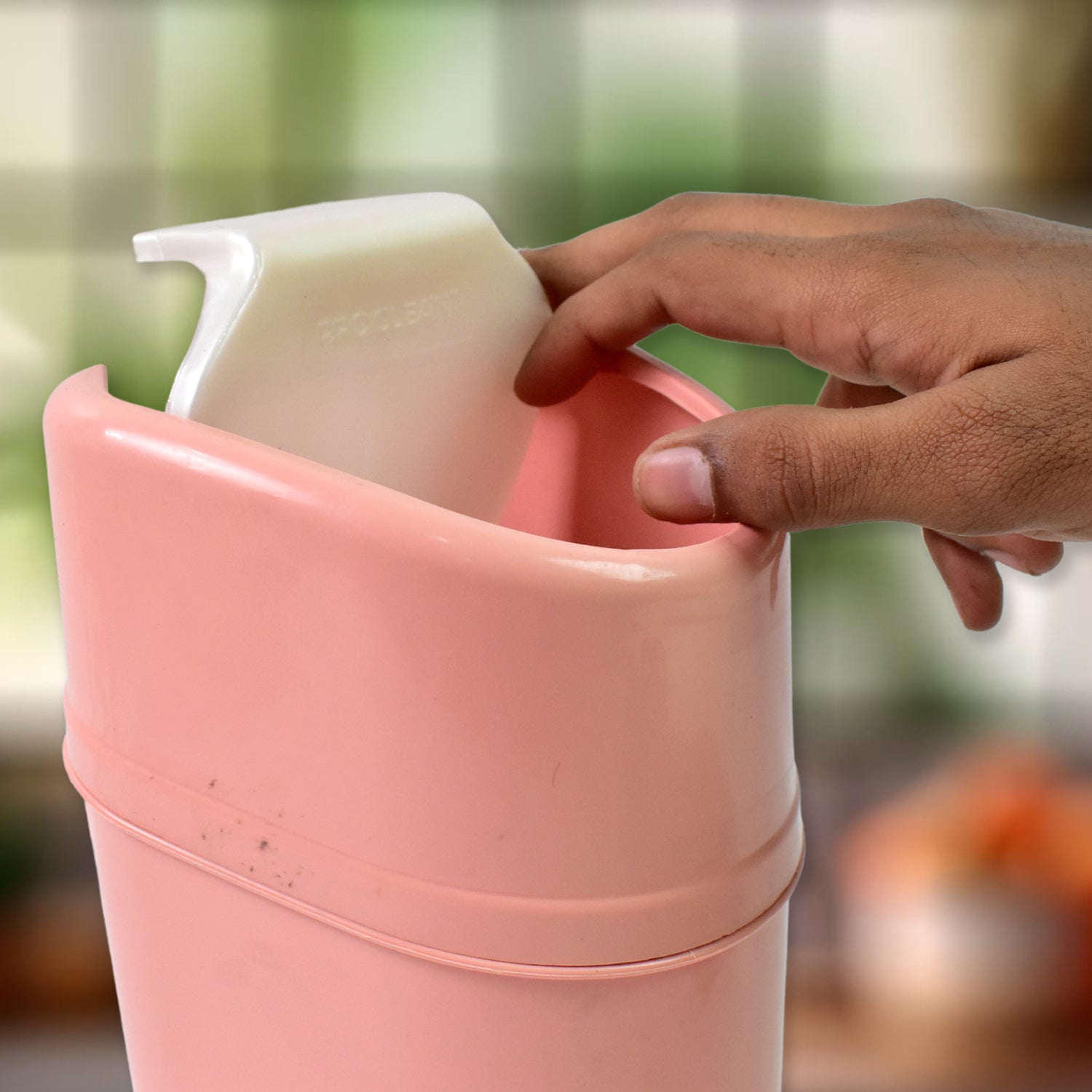Pink mini trash can with lid being used for kitchen waste management