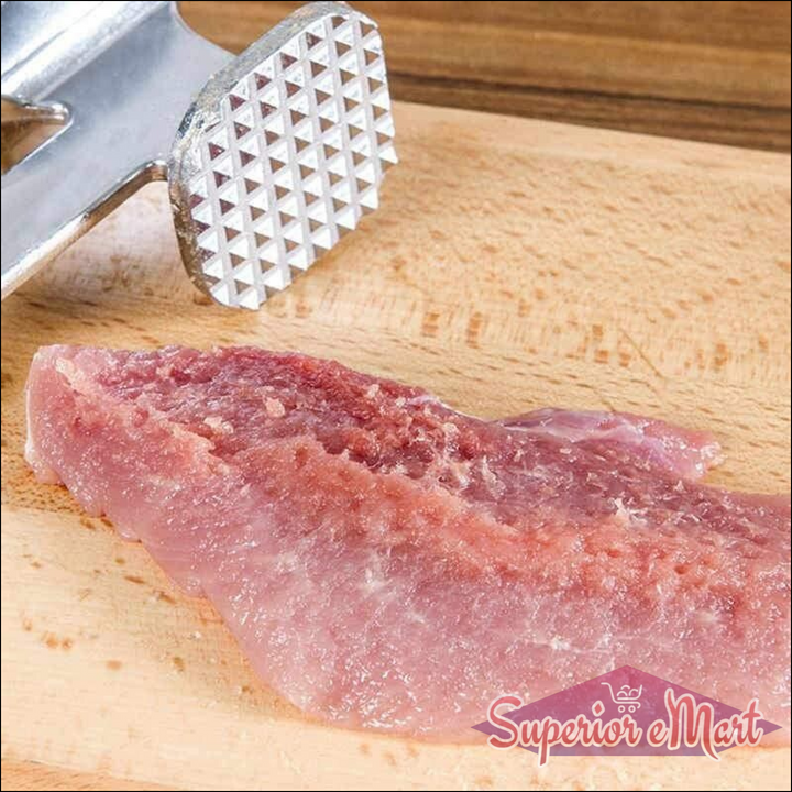 Professional meat tenderizer hammer resting on a wooden cutting board with raw meat