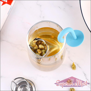 Cute umbrella tea strainer in blue, steeping flowers in a clear glass cup of tea