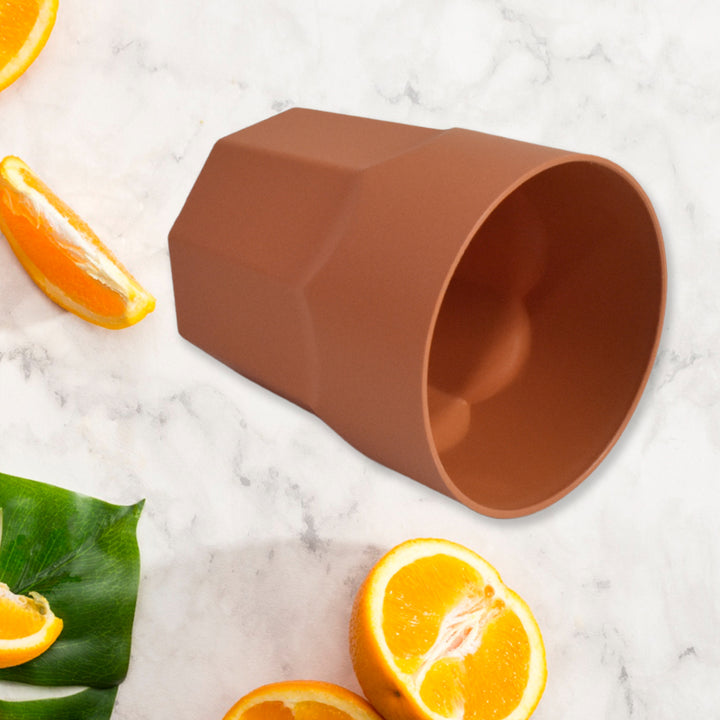 Brown reusable drinking cups 1 pc on a marble surface with fresh oranges and green leaves