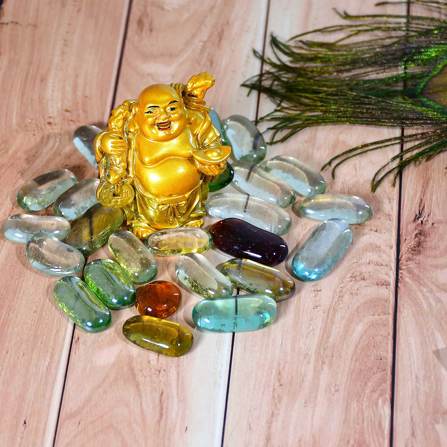 Decorative round marbles for aquarium displayed with a golden Buddha figurine on a wooden surface