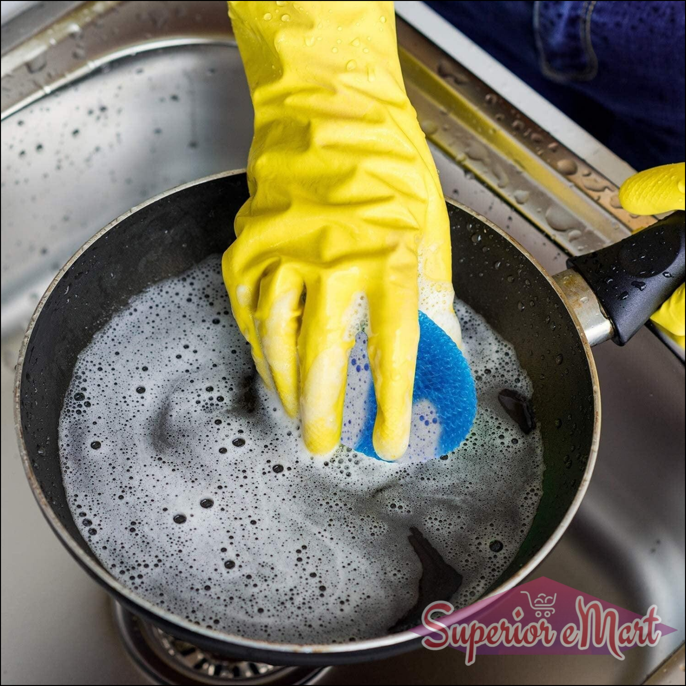 Yellow-gloved hand using nylon scrubbers for dishes on a pan filled with soapy water