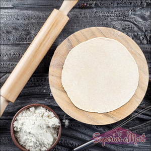Round roti maker for home use with wooden rolling pin and fresh dough on a wooden board