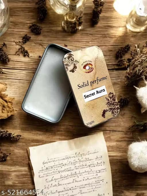 Secret Aura solid perfume presented in an elegant tin with floral design and a vintage backdrop