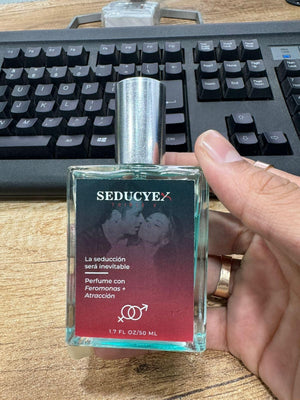 Seducye Triplex extrait de parfum bottle held in hand with silver cap on wooden desk near keyboard