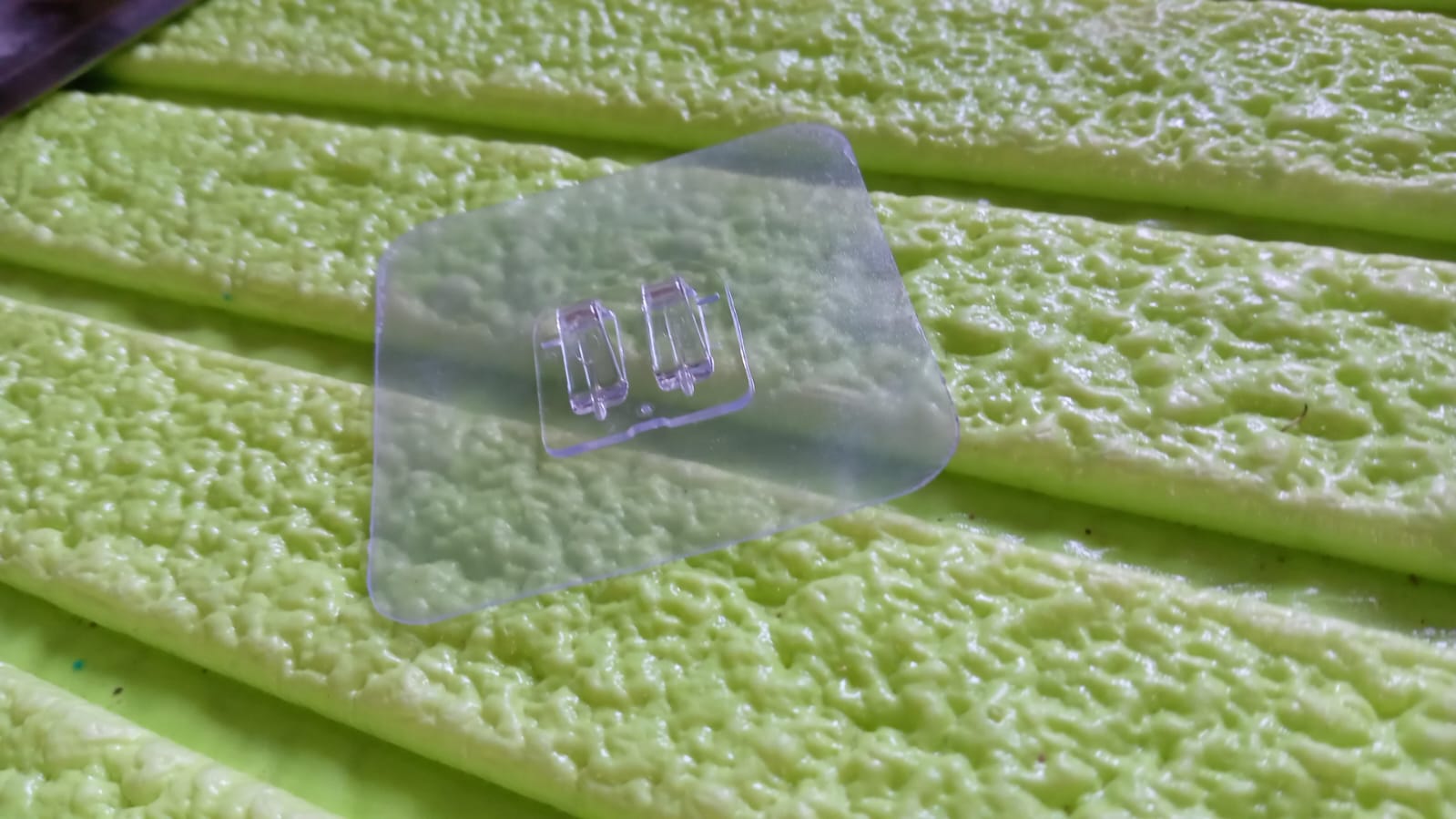 Transparent self adhesive wall hooks on a textured green surface for easy hanging solutions