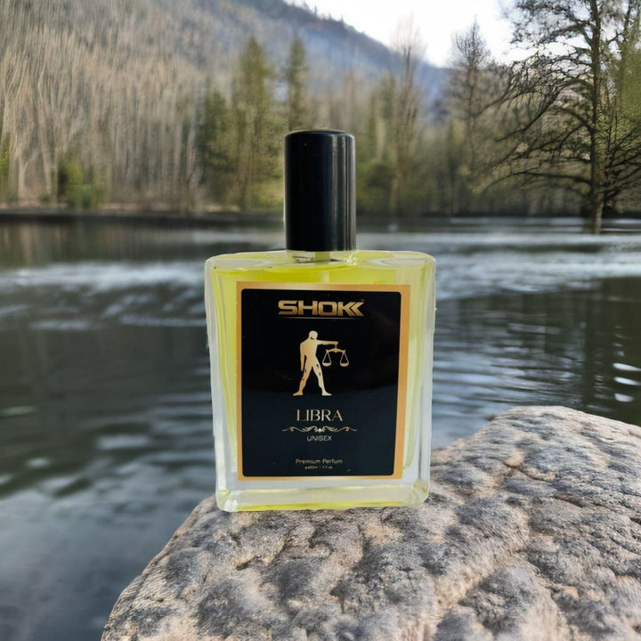Libra Zodiac Unisex Perfum 50ml by Superior eMart placed on a rock near a serene lake with forest background
