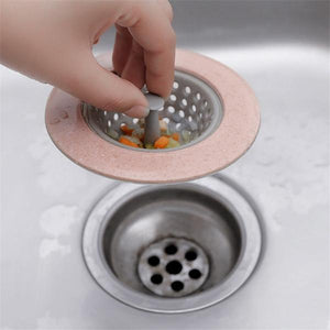 Silicon sink strainer in pink being placed in a kitchen sink to catch food debris
