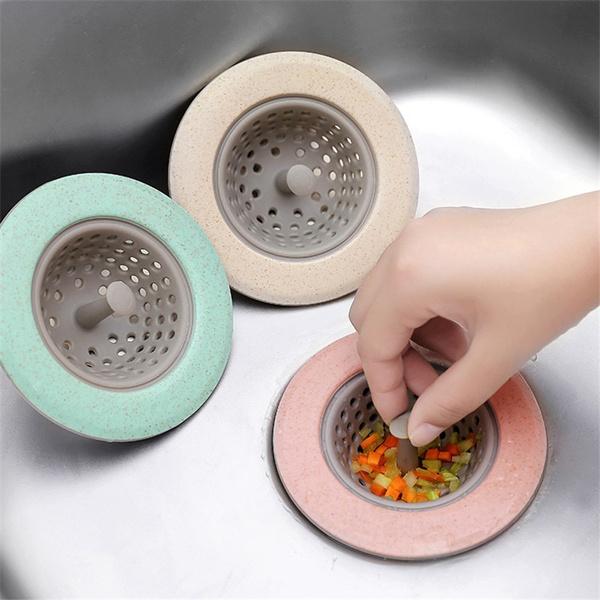 Set of three silicon sink strainers in pastel colors catching food scraps in a kitchen sink