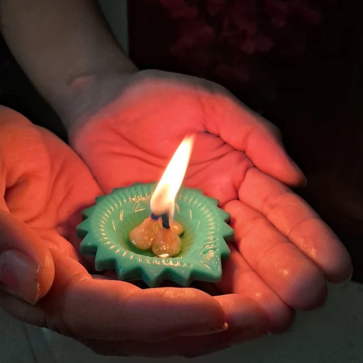 Elegant silicone diya set in a person's hands, featuring a teal design with a lit wick