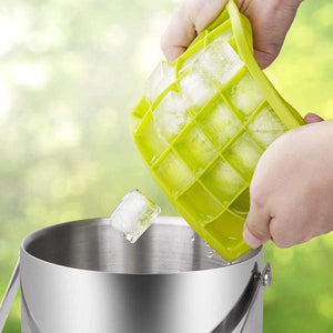 Hands removing ice cubes from vibrant green silicone ice cube trays with lid into a metal bucket