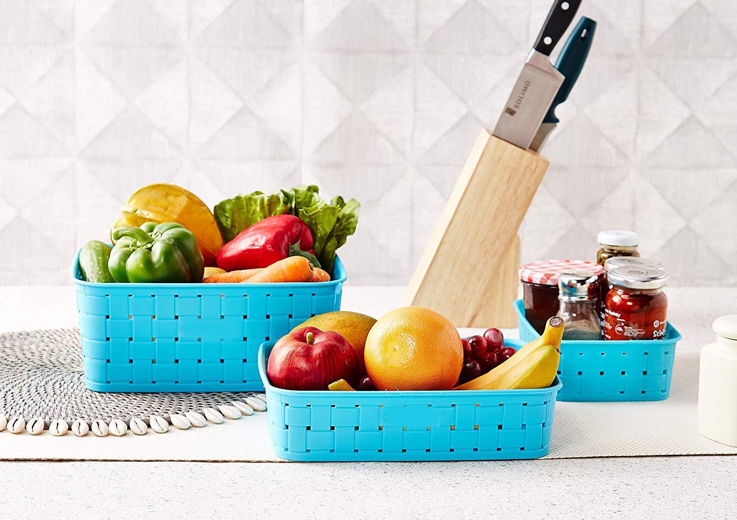 Set of blue smart storage baskets for home filled with fresh fruits and vegetables on a kitchen countertop