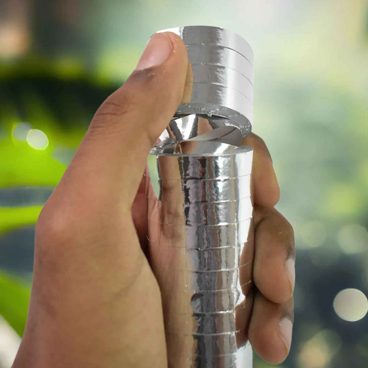 Hand holding smooth ribbon for decorations in shiny silver finish for event styling