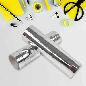 Rolls of shiny silver smooth ribbon for decorations on a crafting workspace with colorful supplies