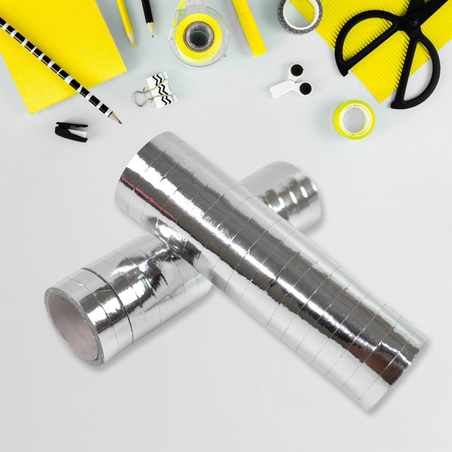 Silver smooth ribbon for decorations with crafting tools and yellow accessories on a white background