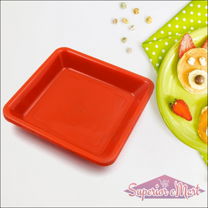 Bright red square dinner plate set on a green polka-dotted tablecloth with snacks