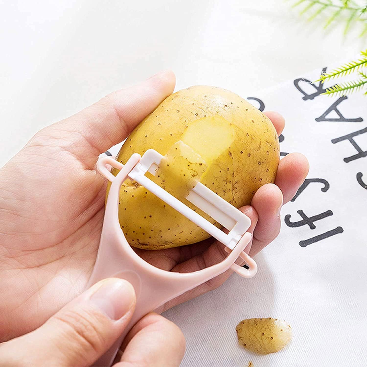 Hand using a stainless steel blade vegetable peeler on a potato for easy peeling