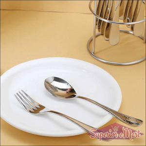Stainless steel cutlery set displayed on a white plate with a holder in the background