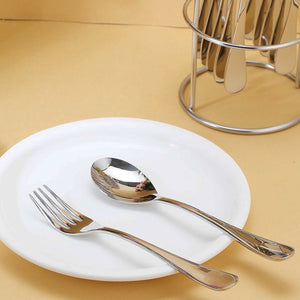 Stainless steel cutlery set displayed on a white plate with a holder in the background