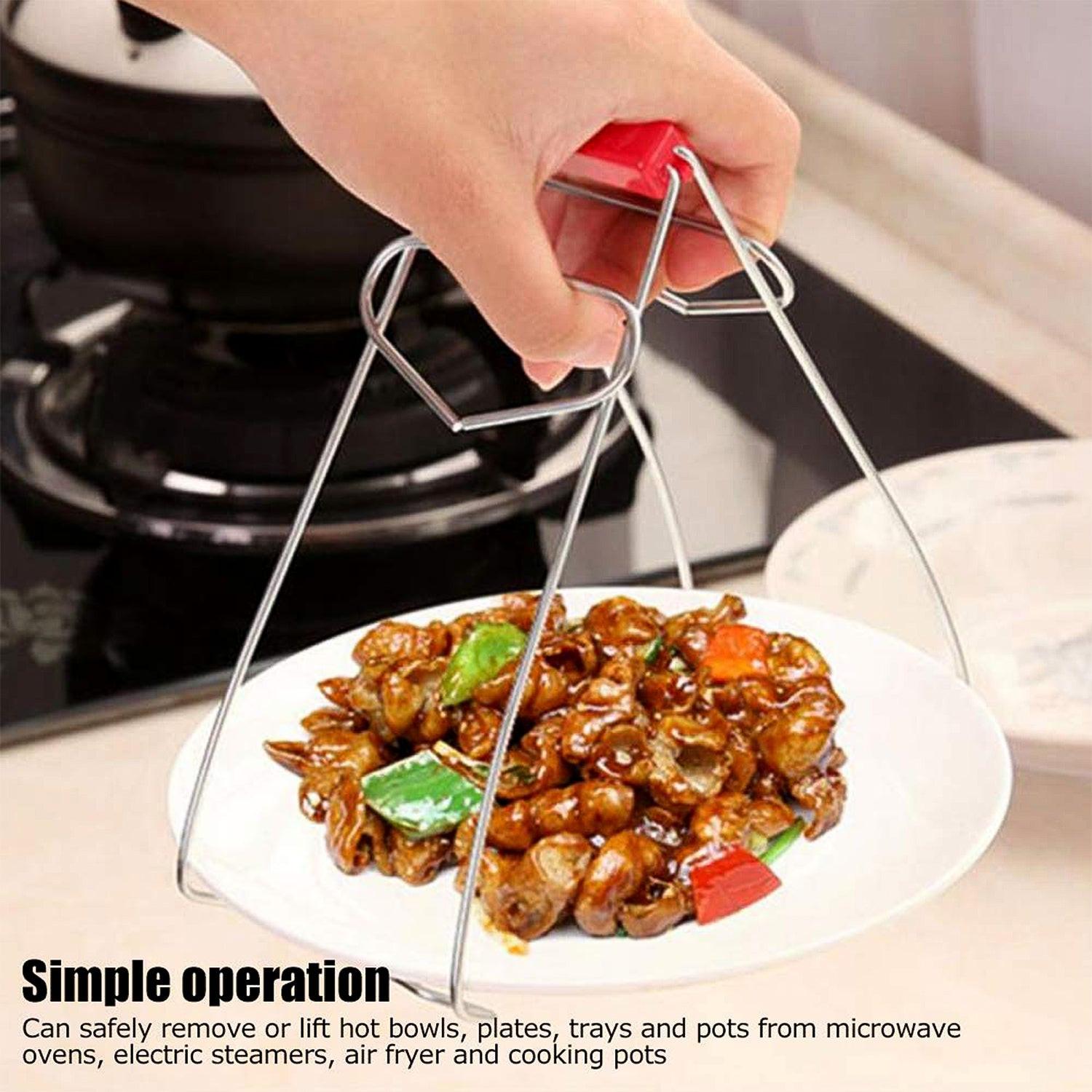 Stainless steel dish gripper tongs in use, lifting a plate of food safely from the kitchen counter.