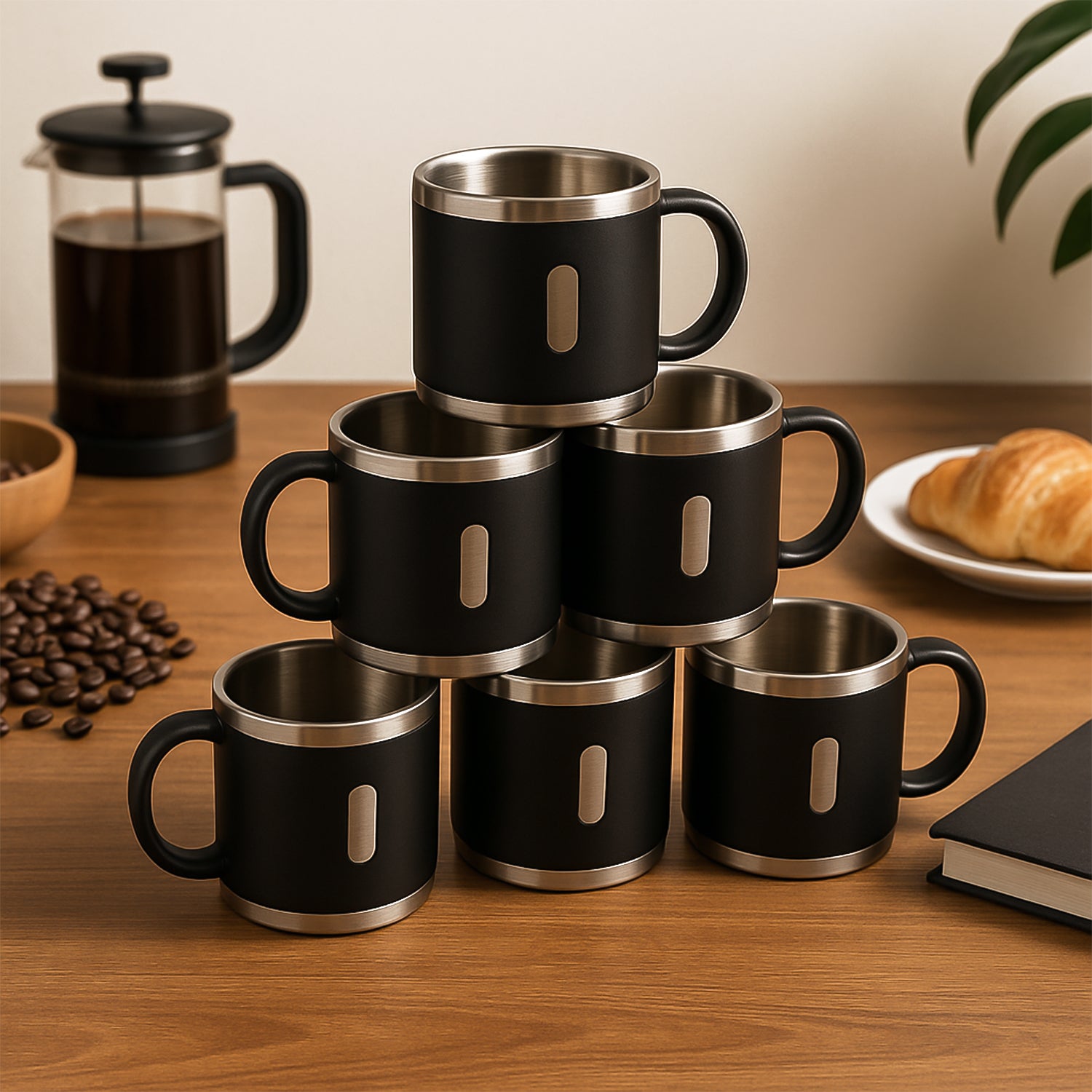 Stainless steel double wall coffee mug set stacked on a wooden table with coffee and pastries