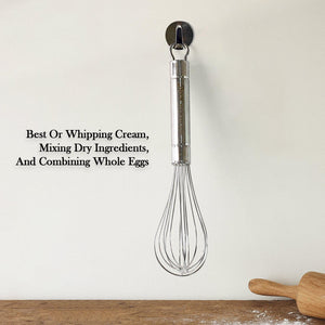 Stainless steel hand whisk hanging on a wall, ideal for whipping cream and mixing ingredients