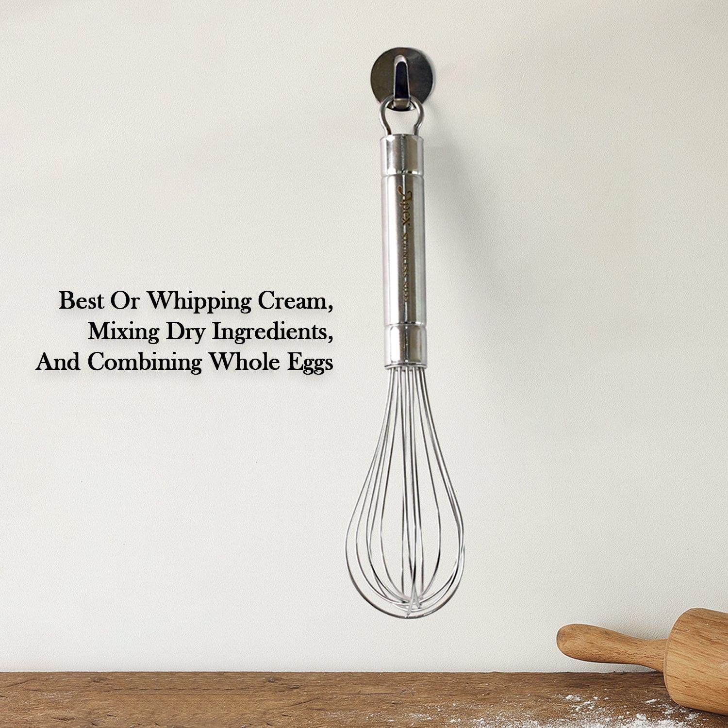Stainless steel hand whisk hanging on a wall, ideal for whipping cream and mixing ingredients