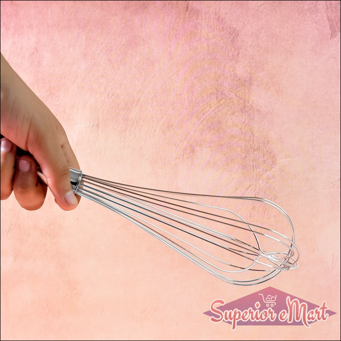 Hand holding a stainless steel hand whisk for mixing and blending ingredients