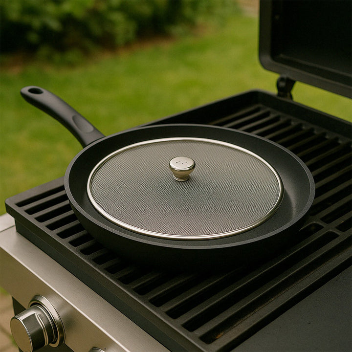 Stainless steel mesh splatter screen placed on a skillet for safe cooking outdoors