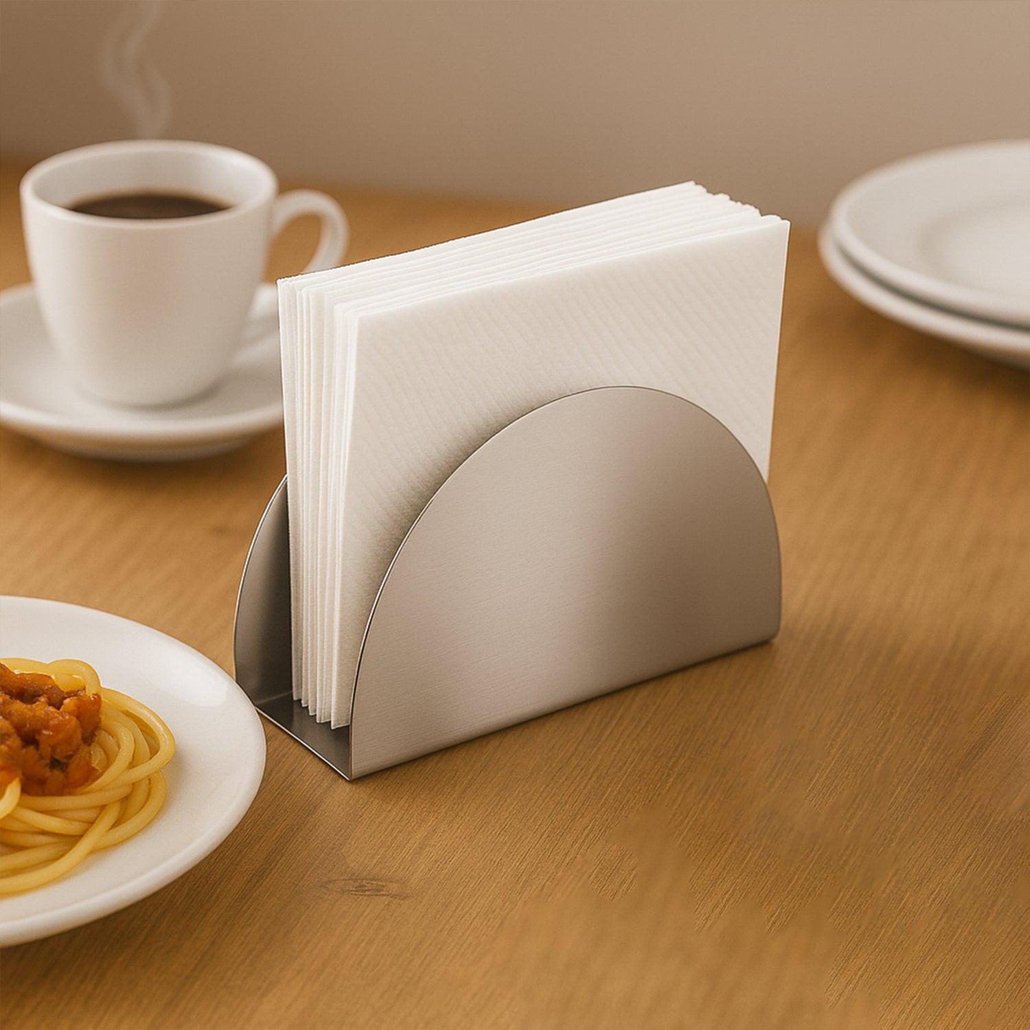 Stylish stainless steel napkin holder with a modern design on a wooden table beside a coffee cup