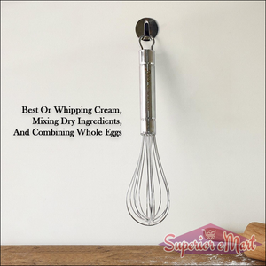 Stainless steel hand whisk hanging on a wall, ideal for whipping cream and mixing ingredients