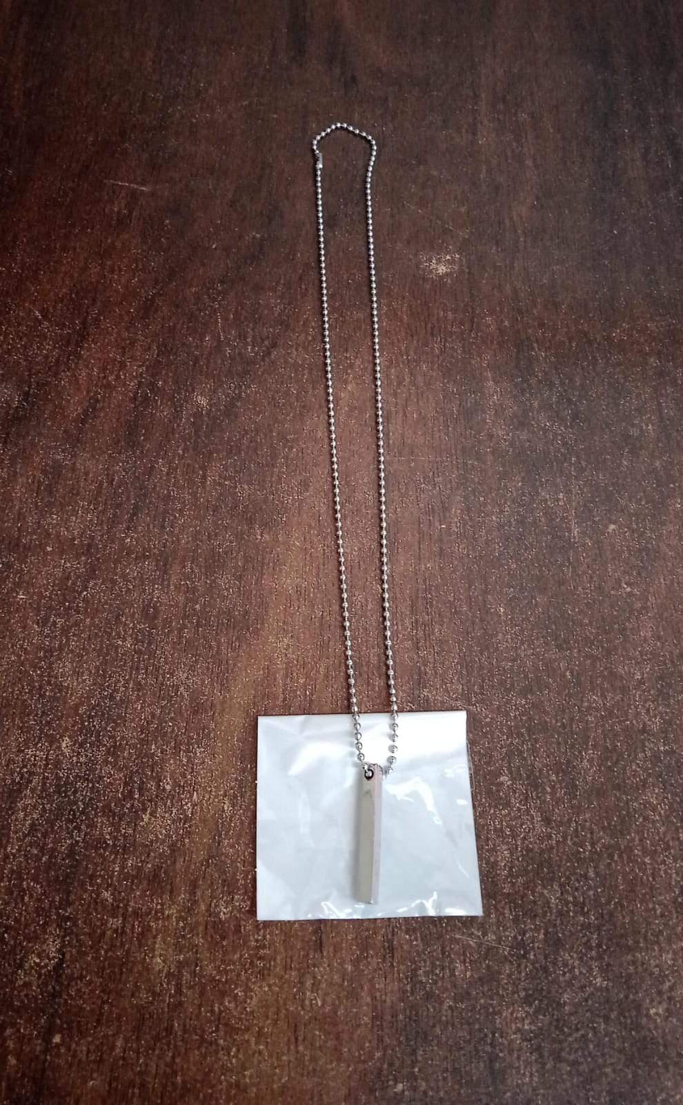 Superior eMart stainless steel stick necklace displayed on a brown wooden surface