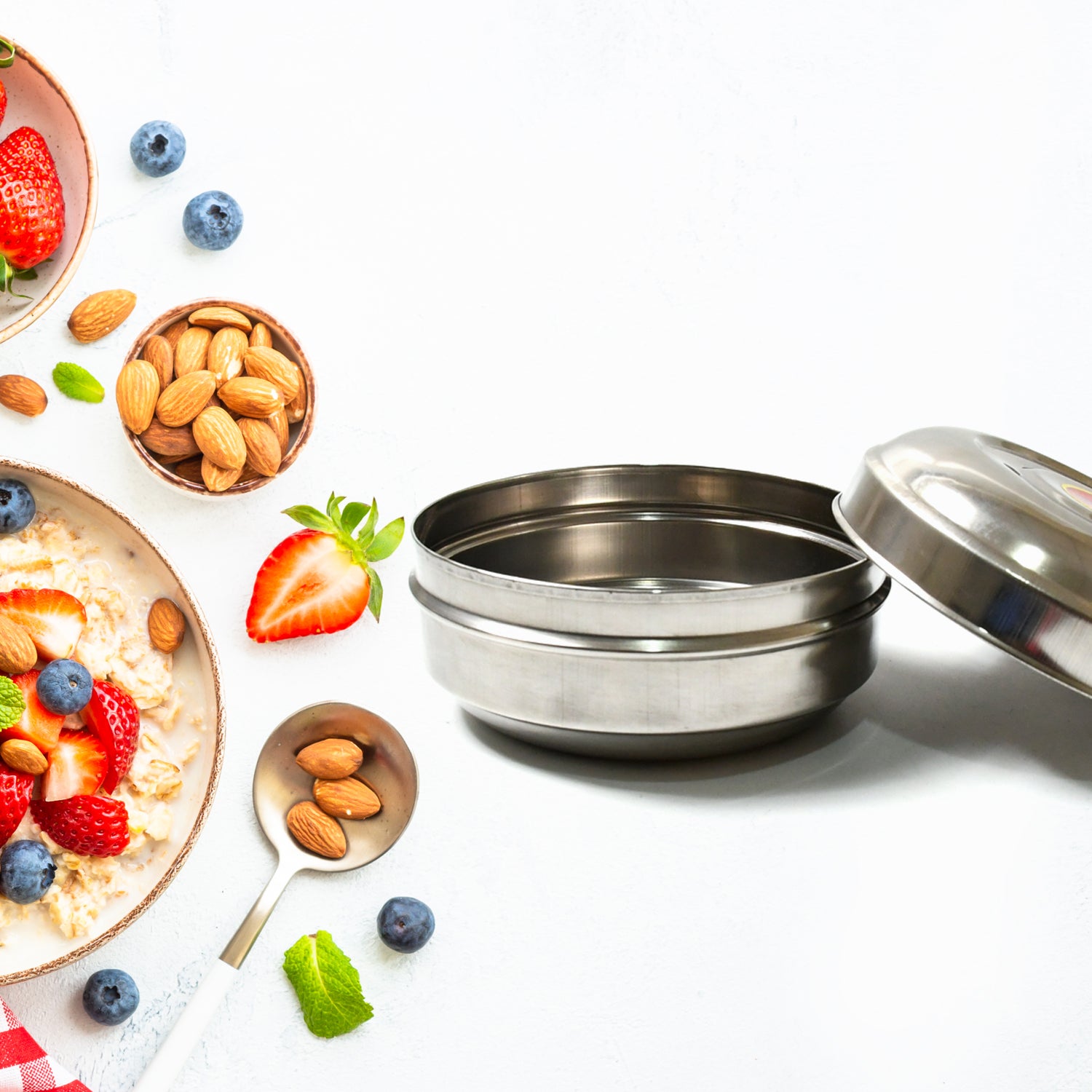 Superior eMart stainless steel tiffin box open with healthy oatmeal topped with fruits and nuts on white background