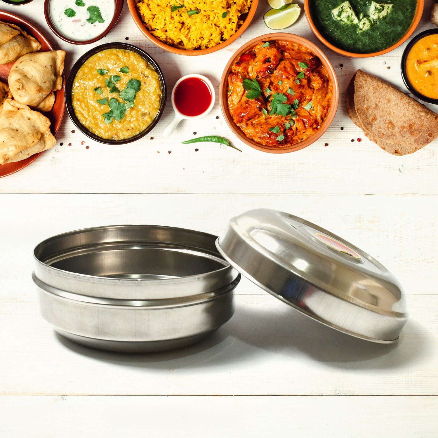 Superior eMart stainless steel tiffin box open with food dishes served above on white wooden surface