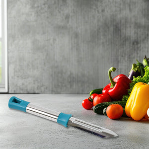 Stainless steel vegetable peeler with an ergonomic handle next to fresh vegetables on a kitchen countertop