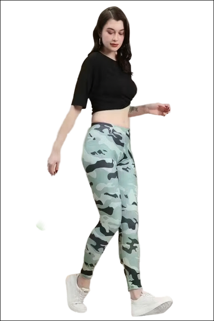Woman in a black short-sleeve crop top and mint green camo print leggings with white sneakers.