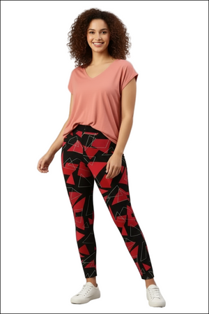 Woman in a coral v-neck tee and black leggings with a red and white geometric triangle print and white sneakers.