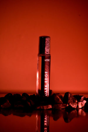 Nyro Dark Edge perfume in a sleek roll-on bottle surrounded by black stones