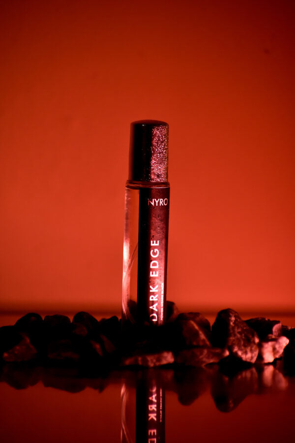Nyro Dark Edge Perfume in Roll-On Bottle, Part of the Elite Set, Against a Dramatic Red Background