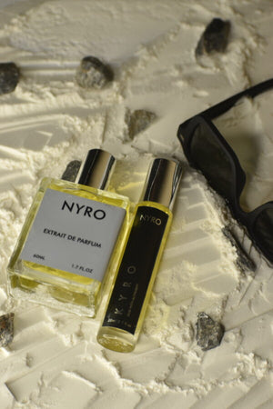 Nyro Kyro Extrait de Parfum in two bottle sizes on a textured surface with sunglasses