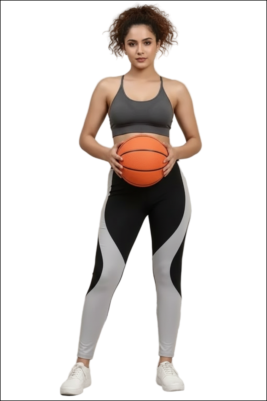 Woman in a dark gray sports bra and black/gray wavy-patterned leggings holding an orange basketball.