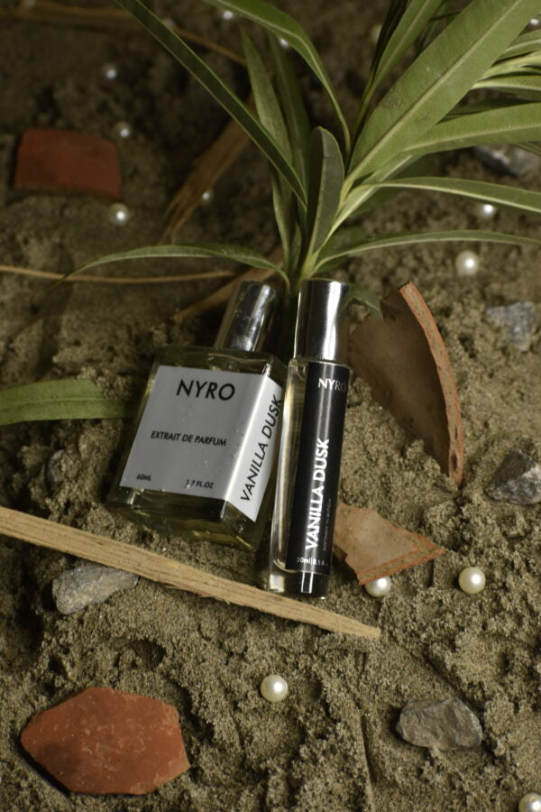 Nyro Vanilla Dusk Perfume Bottle with Rollerball on Earthy Background with Decorative Elements