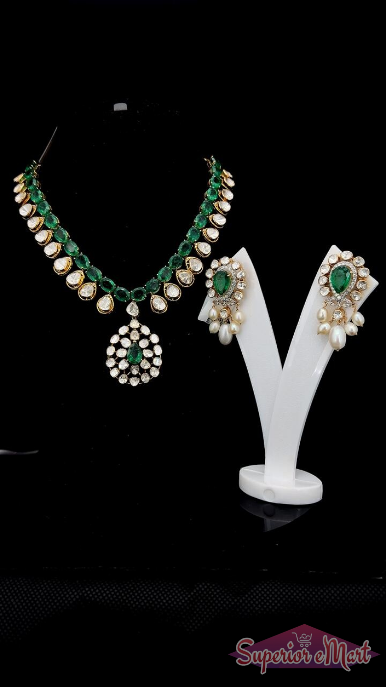 Gold-toned emerald and white stone jewelry set with a floral pendant and matching pearl drop earrings.