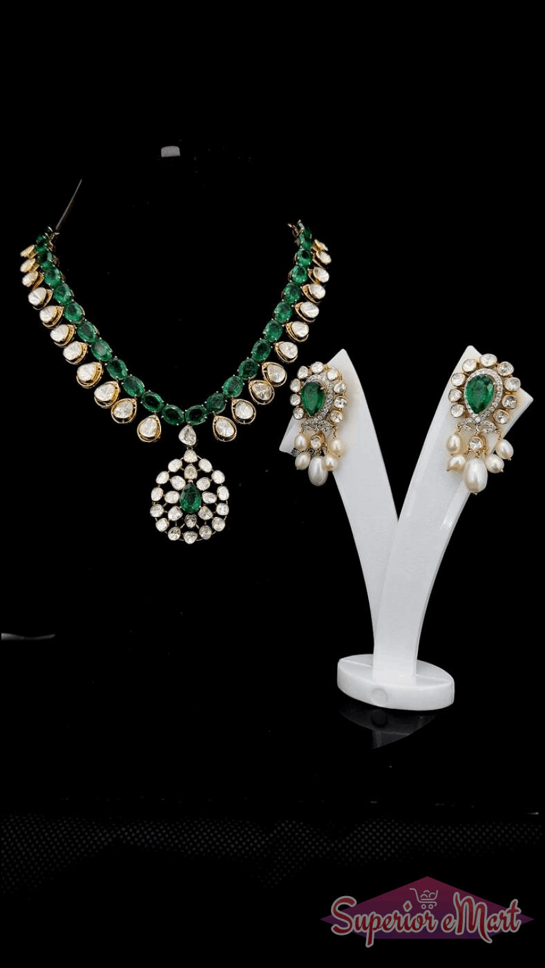 Gold-toned emerald and white stone jewelry set with a floral pendant and matching pearl drop earrings.