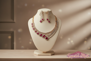 Gold jewelry set featuring an ornate diamond necklace and matching earrings with oval red ruby accents.