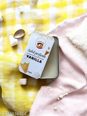 Vanilla solid perfume balm in a tin with a soft cream texture against a yellow checkered background