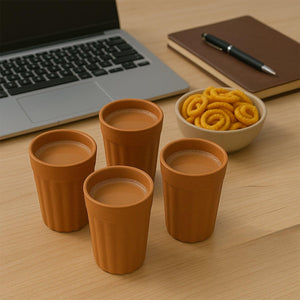 Traditional chai cups set with four terracotta cups filled with chai placed on a wooden table next to snacks