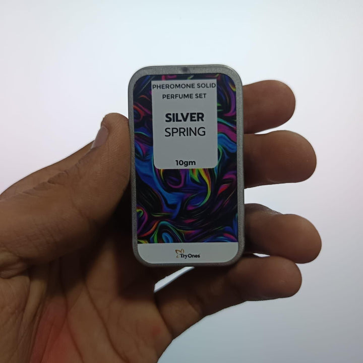 Hand holding silver spring solid fragrance pack of 2 pheromone solid perfume set in 10gm tin