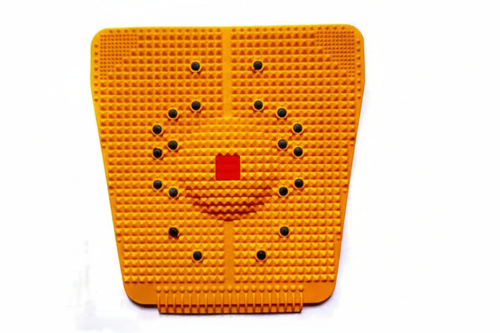 An orange textured foot stimulator pad with a grid of small raised bumps, black circular dots arranged in a circular pattern, and a red square in the center, shown on a white background.